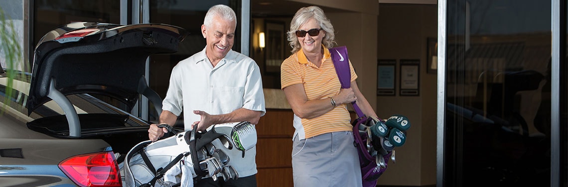 Couple ready to play golf near a SureStay Studio hotel