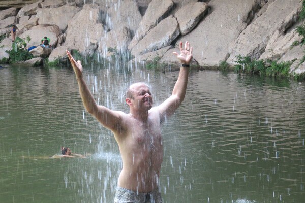 A man standing under a waterfall.