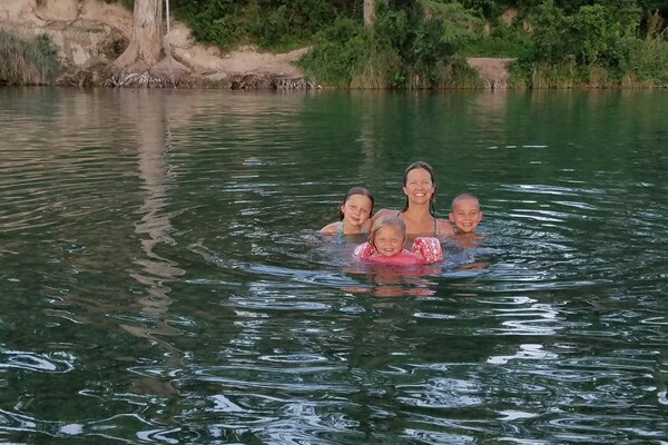 A woman and children swimming in the lake.