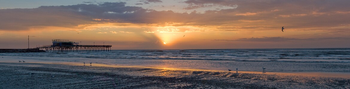 Sun setting along the beach and pier in Galveston.