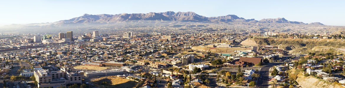 Aerial view of city with mountains in background.