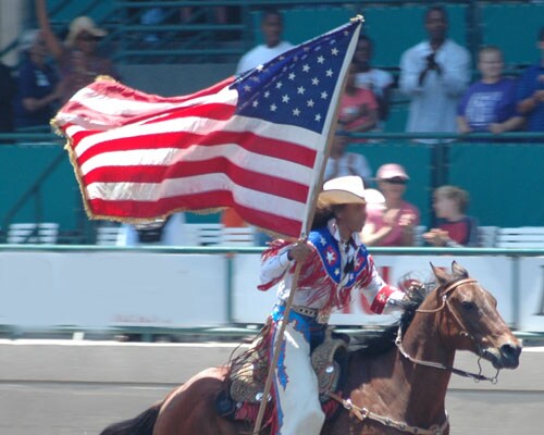 Cowgirl riding a horse waving an American flag