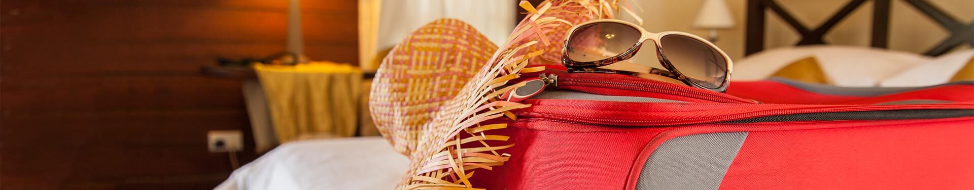 sunglasses and suitcase on a hotel bed